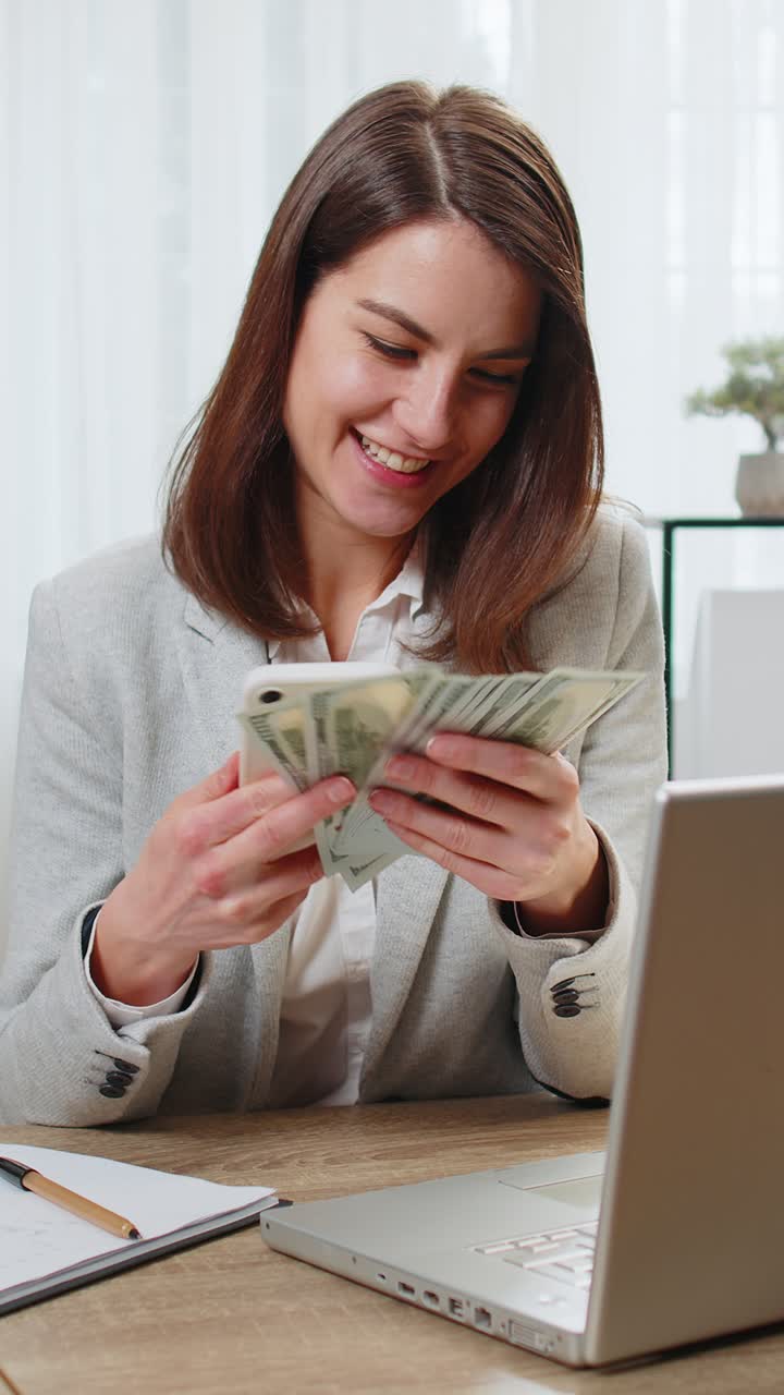 mulher de negócios rica feliz contando dinheiro dividendos em dinheiro usando calculadora de smartphone no escritório em casa