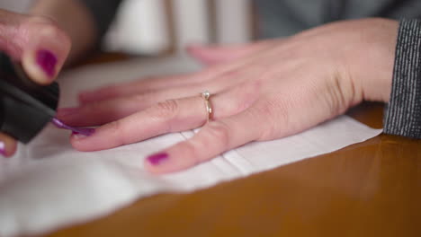 Slow-dolly-across-woman's-hand-with-an-engagement-ring-as-she-applies-nail-polish