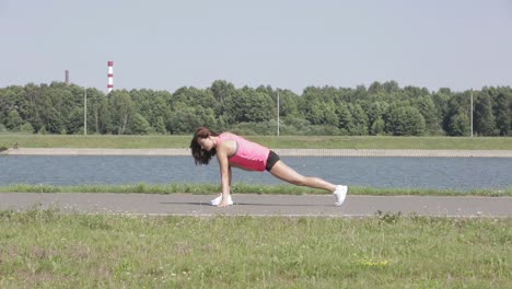 mujer estirándose al aire libre junto a un lago