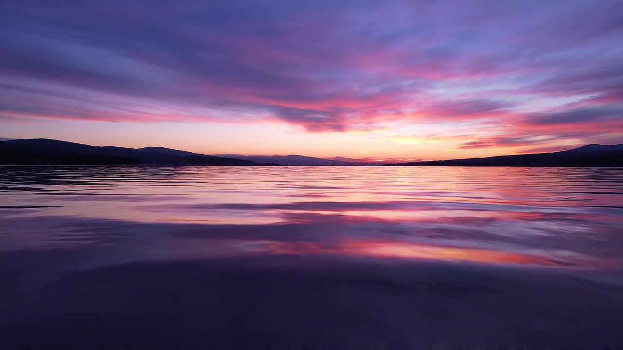 Vibrant purple and pink sunset over calm lake water
