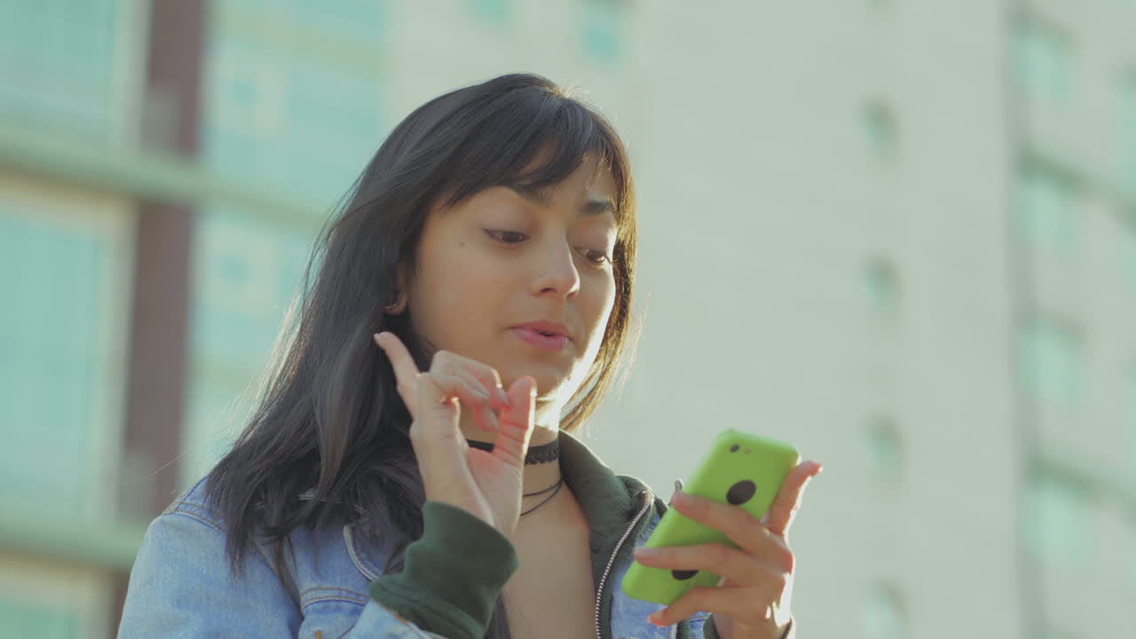 una adolescente sonriente enviando mensajes de texto en su teléfono inteligente.