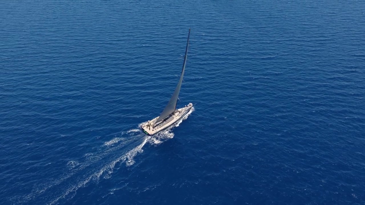 Yacht a vela di lusso che naviga in mare aperto di un blu profondo a Porto Cervo, Sardegna, Italia. Ripresa aerea