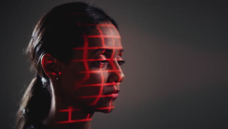 facial recognition technology concept as woman has red grid projected onto face in studio