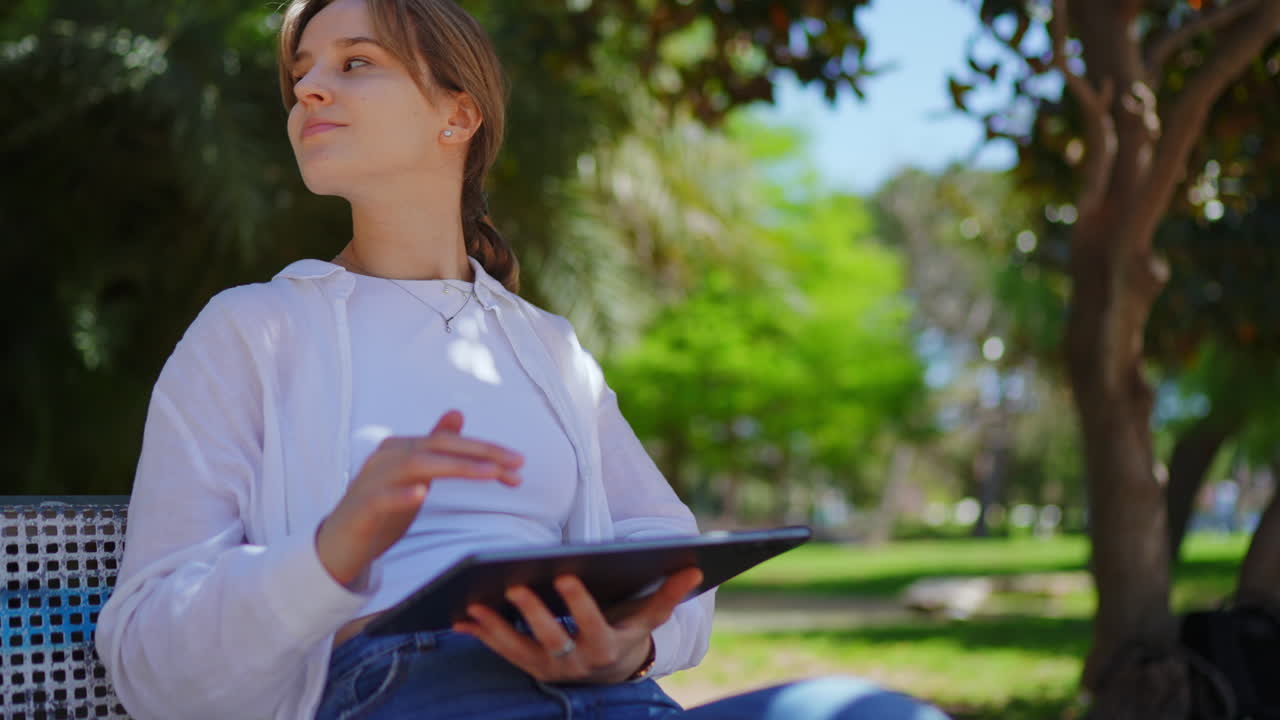 mujer joven que usa la tableta en un parque
