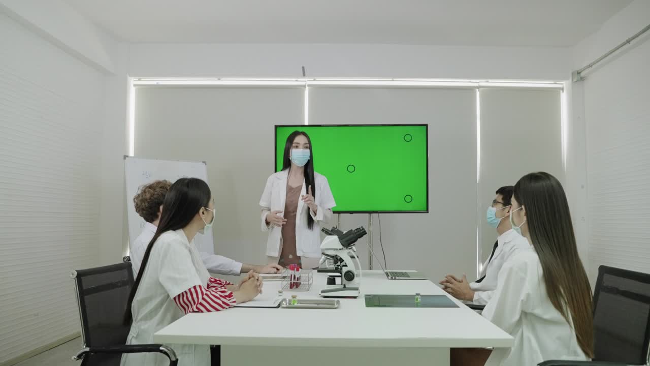 의사의 회의에서, 젊은 여자의 의사는 녹색 화면에서 그녀의 의학적 정보를 제시하고있었습니다.