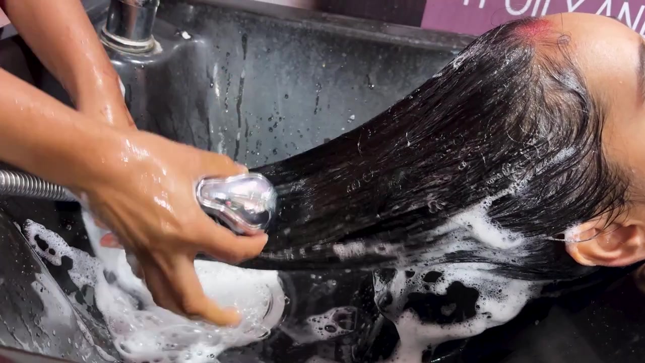 Giovane ragazza che si fa lavare i capelli nella vasca di un salone