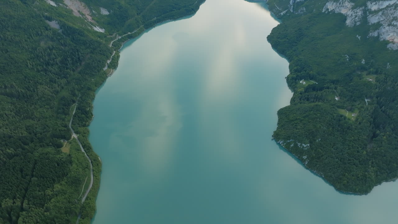 Wide aerial drone footage of Lake Molveno in northern Italy during the fall with bright turquoise colors.