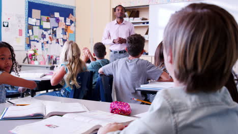los niños de la escuela primaria levantan las manos al maestro