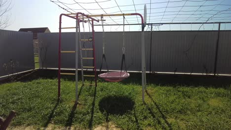 un patio de recreo vacío en un césped verde, un columpio balanceándose silenciosamente en el viento 4k