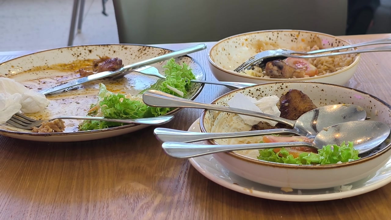 Diversi piatti sono su un tavolo da pranzo. Il cibo servito è stato completamente consumato. Solo avanzi disordinati e scarti di cibo rimangono sparsi sui piatti vuoti