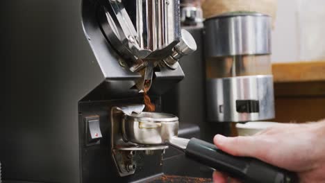 Primer-Plano-De-La-Mano-De-Un-Barista-Masculino-Caucásico-Preparando-Café-Para-La-Máquina-De-Café-En-La-Cafetería