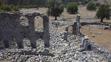 volando sobre las antiguas ruinas rocosas de la ciudad de aperlai con árboles en el fondo, turquía