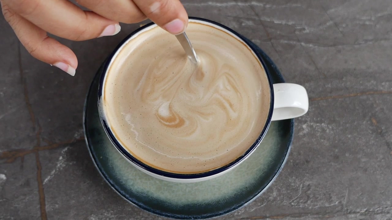 Persona che mescola una tazza di caffè latte