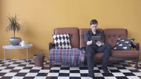 man using tablet on a sofa