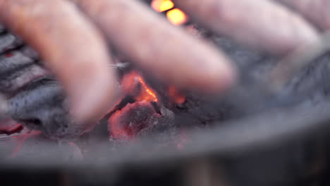 slow motion macro pull out of sausages grilling on fiery and smokey bbq grill