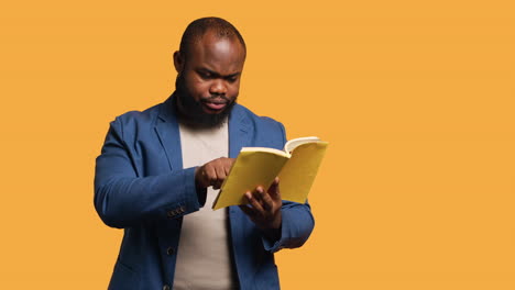 man struggling to read book with small font, pointing finger to words