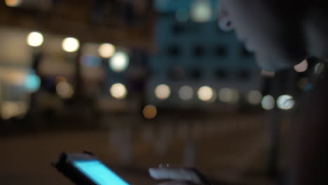 Mujer-Escribiendo-En-El-Teléfono-Celular-Caminando-En-La-Ciudad-De-Noche