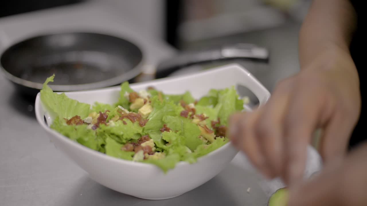 Woman chef cook preparing a salad and adding chopped chicken breast at a local restaurant diner cafe in Mexico latin america