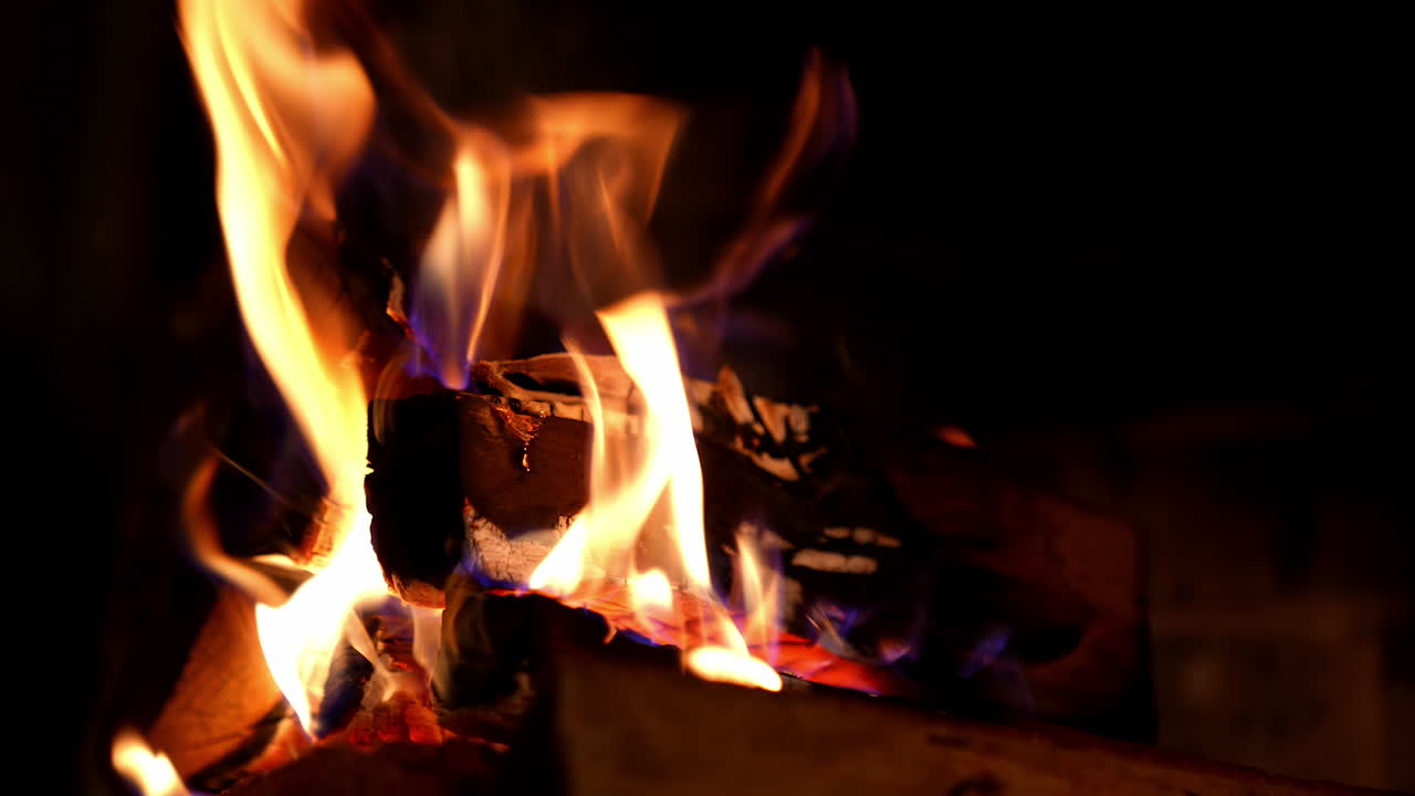 Cropped view of the wood burning in a fireplace during the night. Warm cozy fire in a fireplace. Autumn and winter holidays. Home cosiness concept