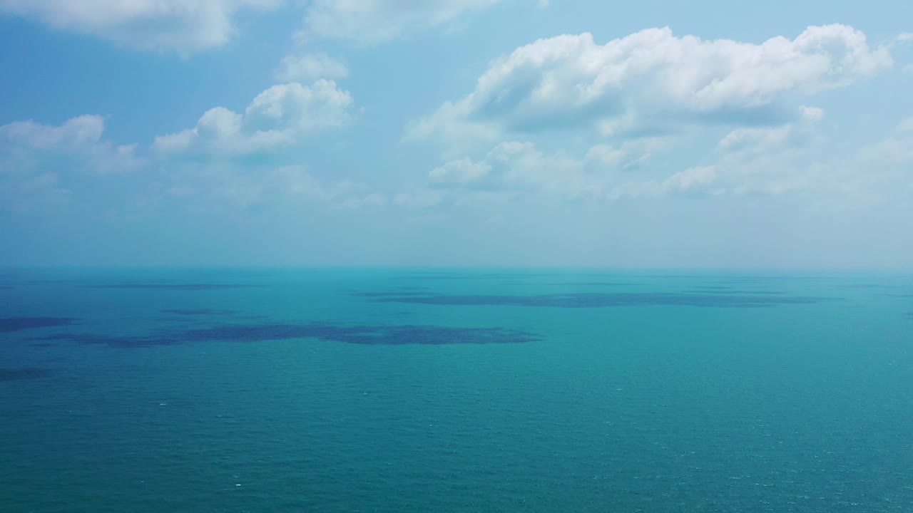 Misty sky with clouds rising over ocean horizon shining turquoise sea surface near shoreline of tropical island, Cambodia