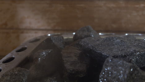 pouring water on hot sauna rocks to generate steam inside the sauna