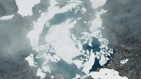 vista de arriba hacia abajo de un lago de montaña con témpanos de hielo y niebla