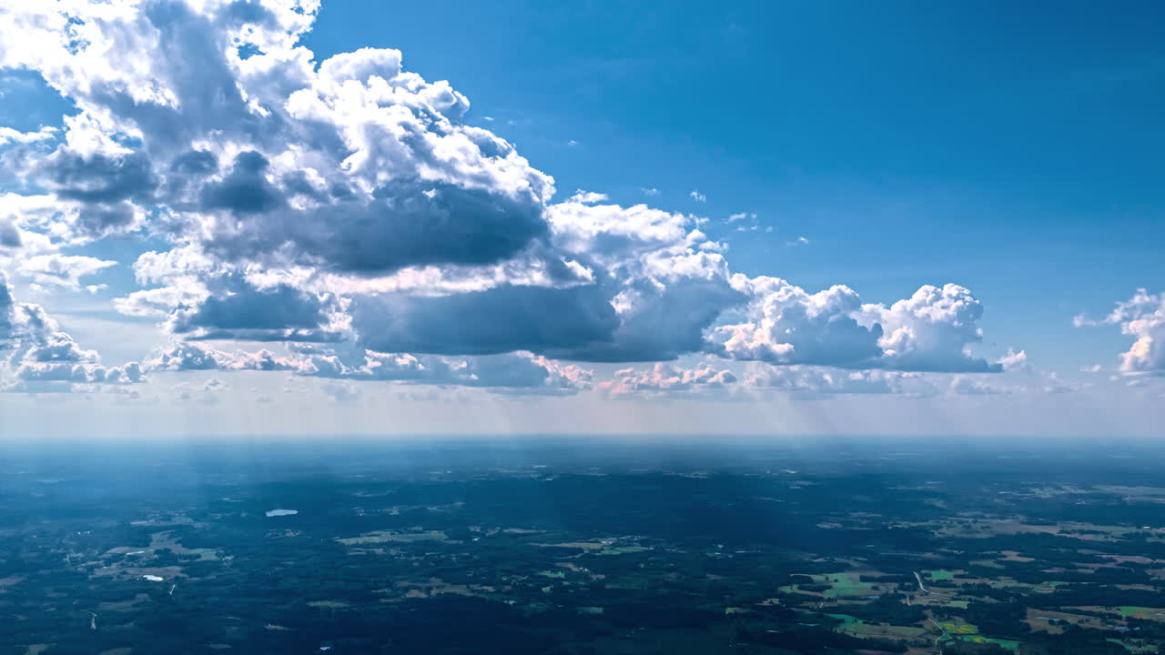 Dense clouds and light rays moving over fields and countryside, sky backdrop texture