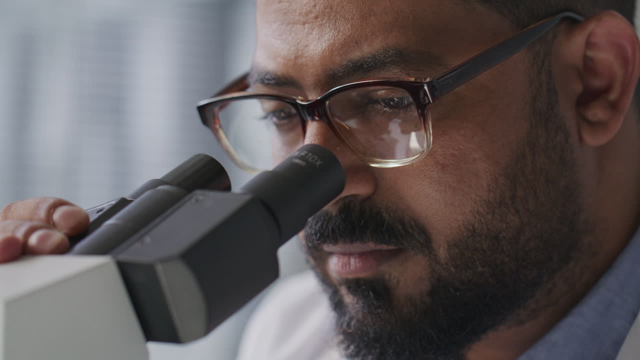 Scienziato che esamina un campione attraverso la lente del microscopio in laboratorio.
