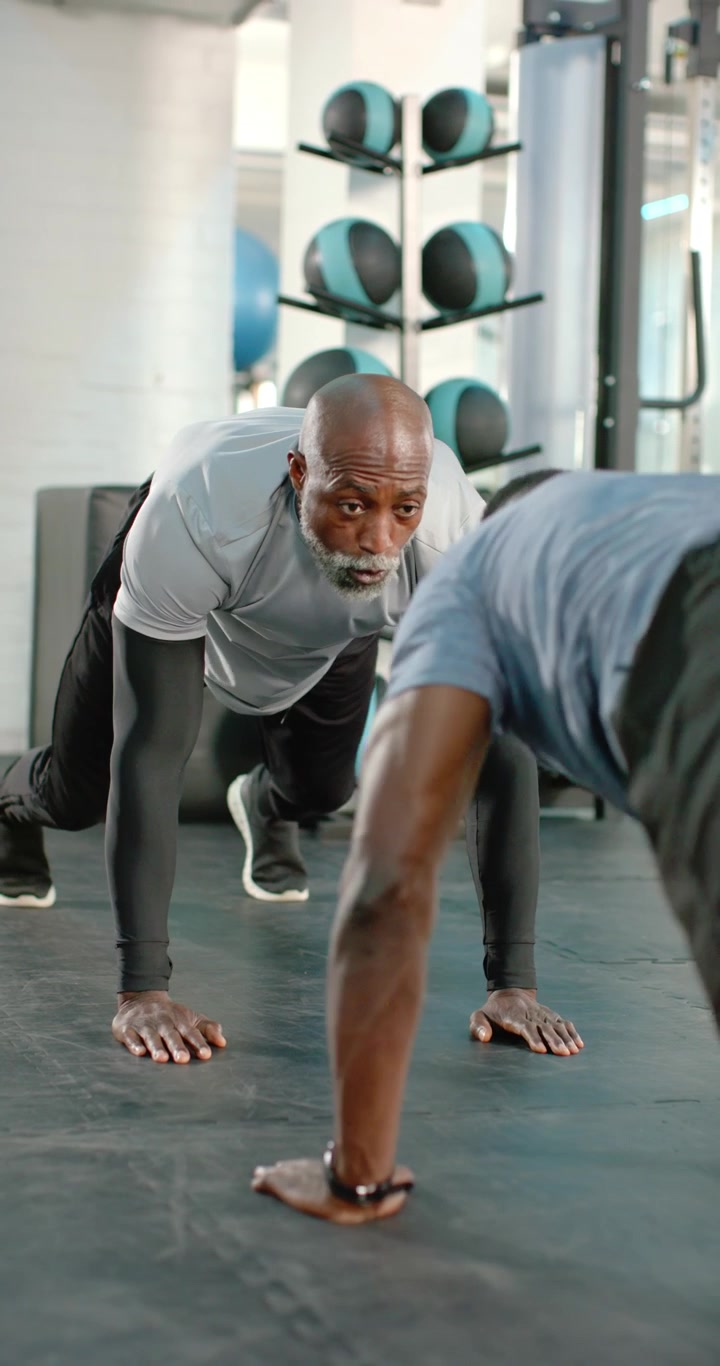 Vertical video: After demo African American male coach and trainee doing pushups at gym for form