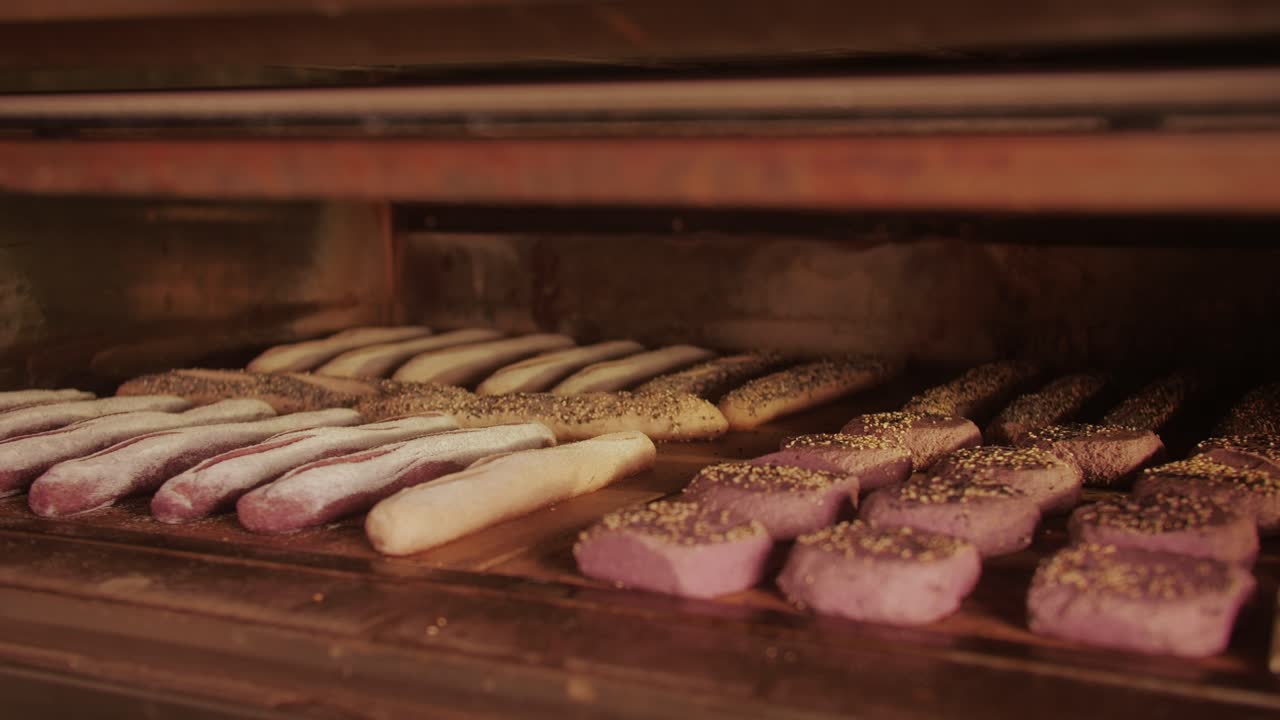 Bakery chef making different various of fresh Artesian buns and baguettes using traditional recipe close-up. Young man kneading dough. Artisan bread is making by skill bakers using natural and high-quality ingredients. Food with health and flavour benefits. Bakery shop and market