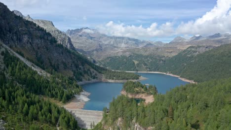 lago di devero in alpe devero with clear waters surrounded by alpine trees and rugged mountains, aerial view