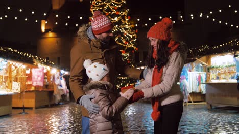 happy family with gift at christmas market in city.winter holidays and celebration concept – happy family with gift at christmas market on town hall square in tallinn, estonia