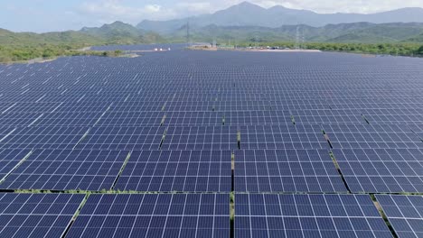 Gran-Campo-De-Paneles-Solares-En-Un-Pintoresco-Paisaje-Montañoso,-Antena-Hacia-Adelante