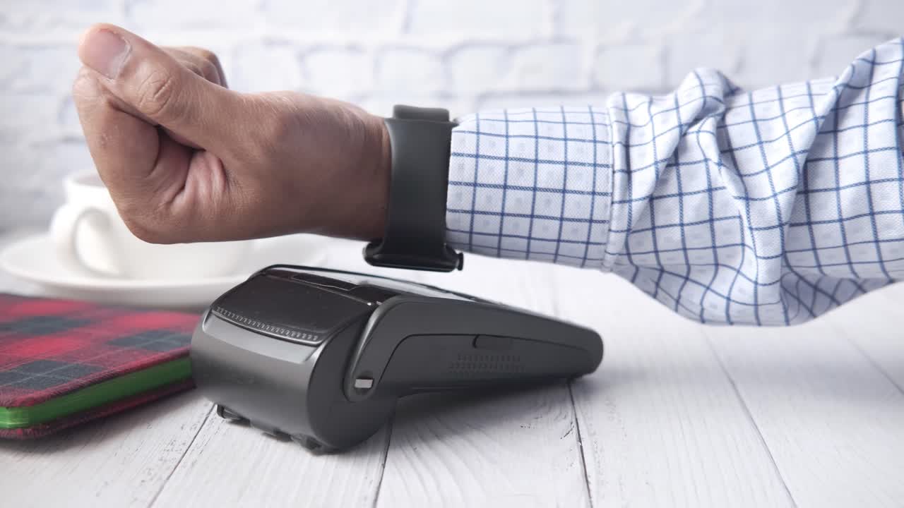 persona que paga con un reloj inteligente en un restaurante