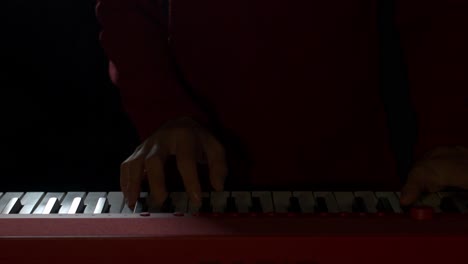 toma cenital de las manos de un pianista hábil tocando un piano eléctrico rojo