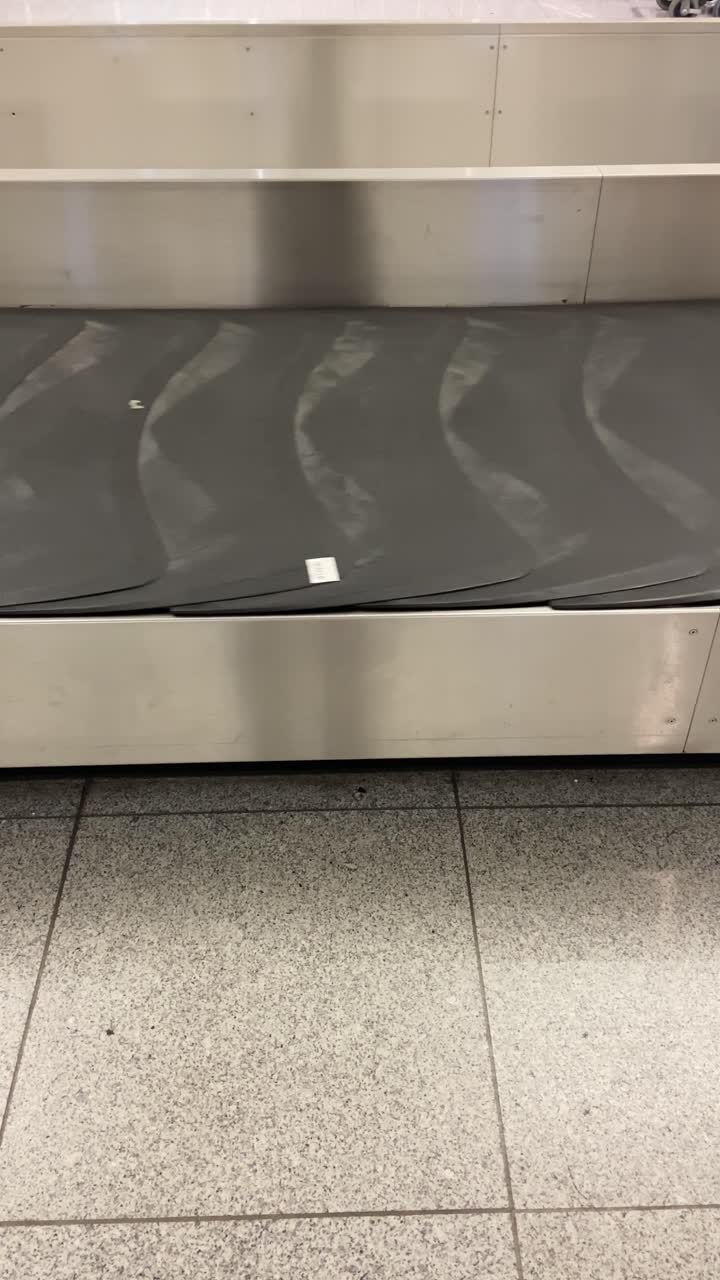 Empty luggage carousel or conveyor belt in airport terminal. Rotating belt with missing bags and suitcases. Delayed flights or mishandled luggage. Travel Influencer pov ugc style filming phone camera