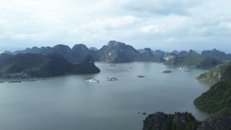 zoom in movement above boats and dramatic karst landscape in cat ba bay