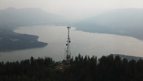 aerial view of radio tower on top of mountain with lake as background