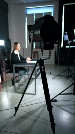 soffit directed on the woman sitting at desk. studio footage of a program or blog. vertical video.
