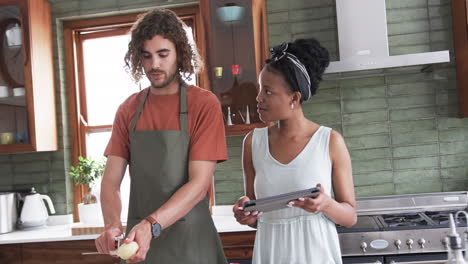 diverse couple, a young african american woman and caucasian man, cooking in a home kitchen