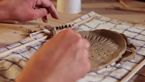 pottery in the studio - young woman makes patterns on a piece of clay