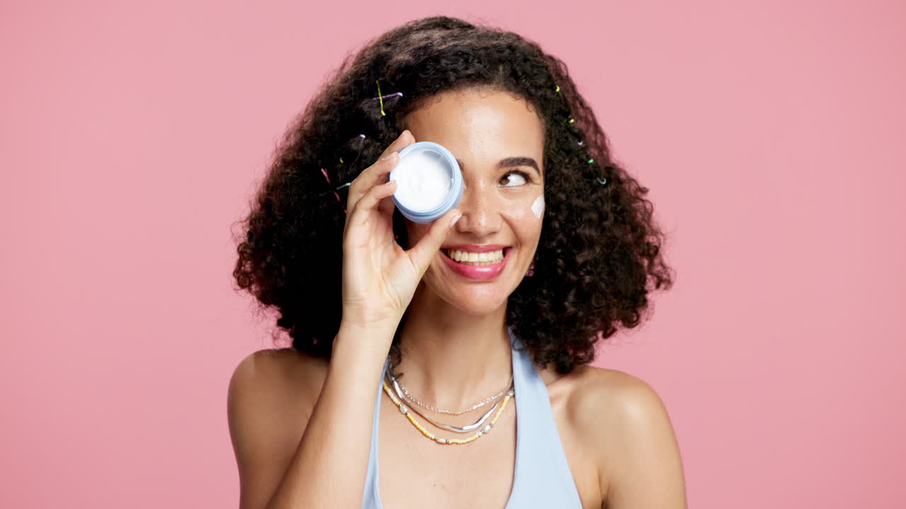 Donna con i capelli ricci che applica la crema per il viso