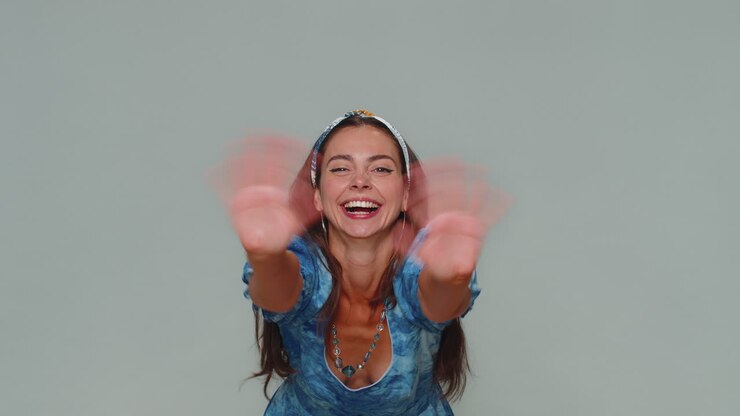 Bella donna che appare dal basso salutando con la mano, accogliendo con un sorriso amichevole e ospitale