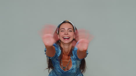 una hermosa mujer aparece desde abajo saludando con la palma de la mano, saludando con una hospitalaria sonrisa amistosa