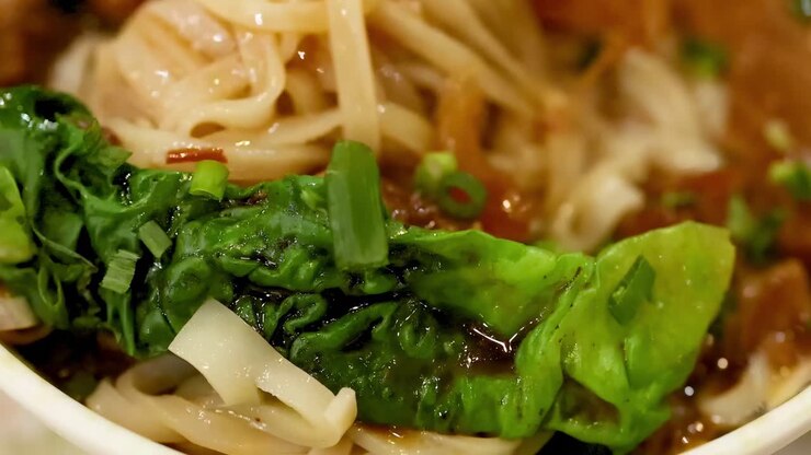 Bacchette che sollevano noodles da un piatto saporito