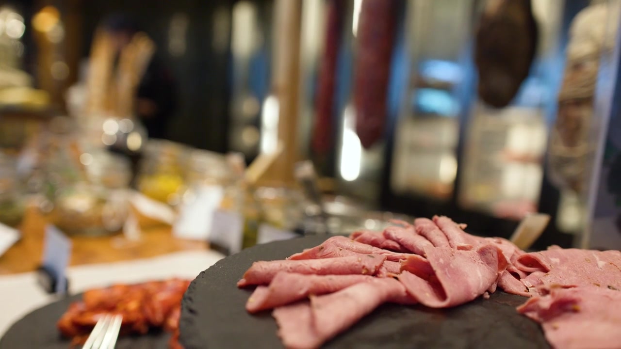Primo piano di roast beef affettato e salumi su un piatto nero a un buffet.