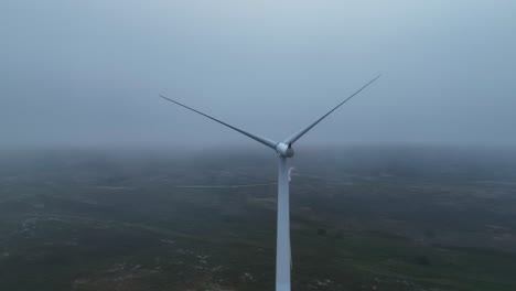 rotating shot of a white windmill along the highlands on a cloudy day