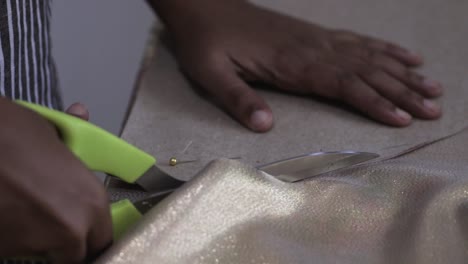 asian female hands cutting fabric circular pattern on a work table with a sharp scissor close up b roll clip