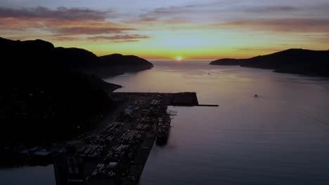 aerial small boat heading toward sun rising out of the ocean, lyttelton