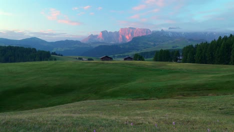 sunrise over alpe di siusi in the dolomites, italy, with green meadows, alpine huts, and the seceda mountains illuminated by morning light, capturing south tyrol’s natural beauty.